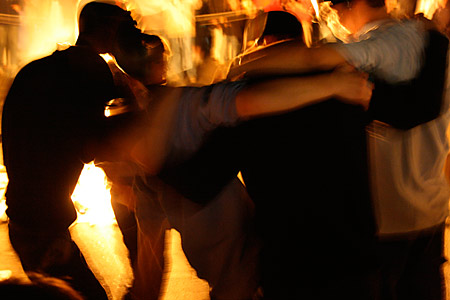 Viele Männer und manche Frau tanzen um das Feuer
